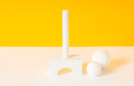 シゴキゴムを折り曲げてマスカラ容器に挿入する工程を自動化。納期短縮と品質向上を実現